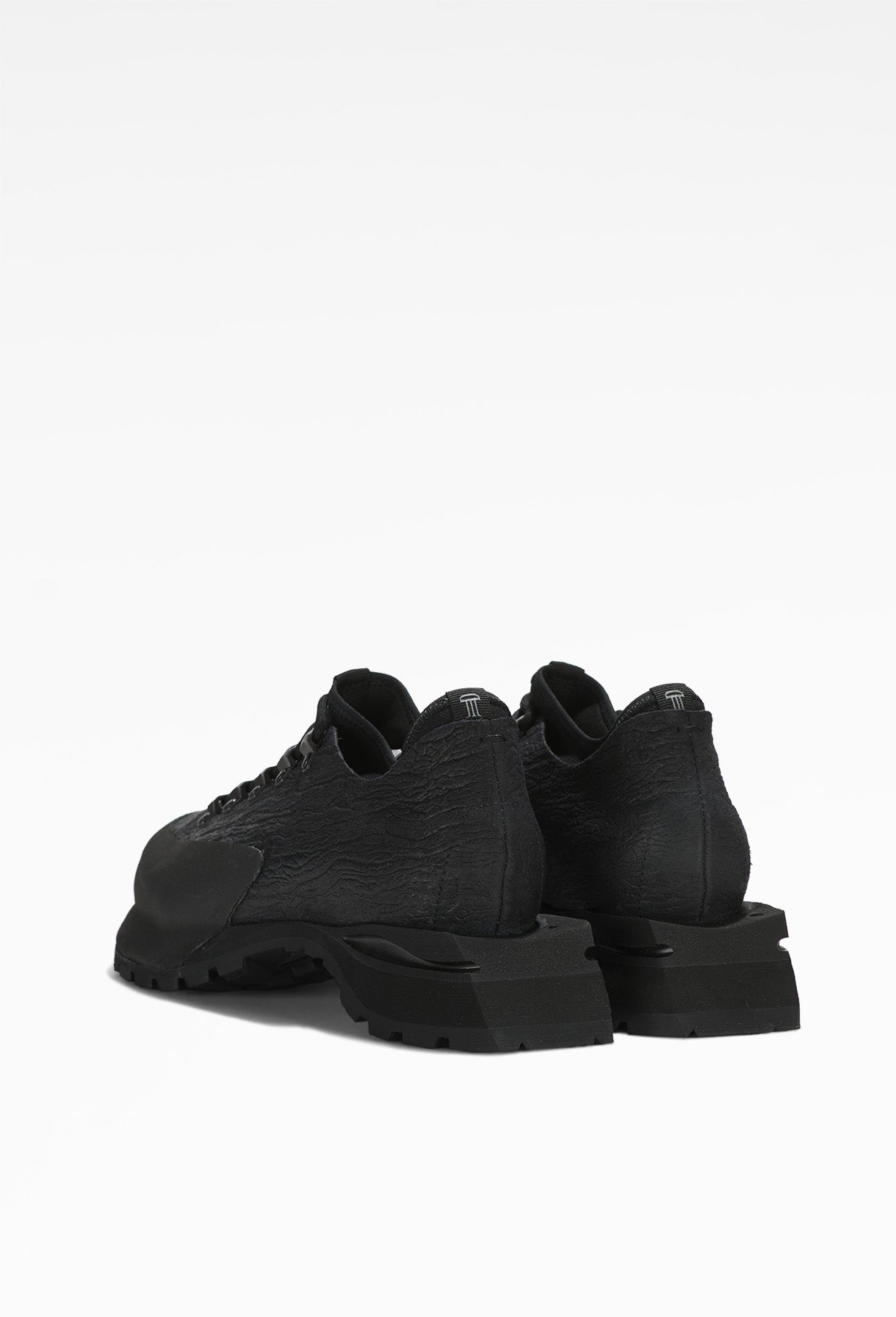 Black lace-up shoes with textured material, thick soles, displayed from the back angle.